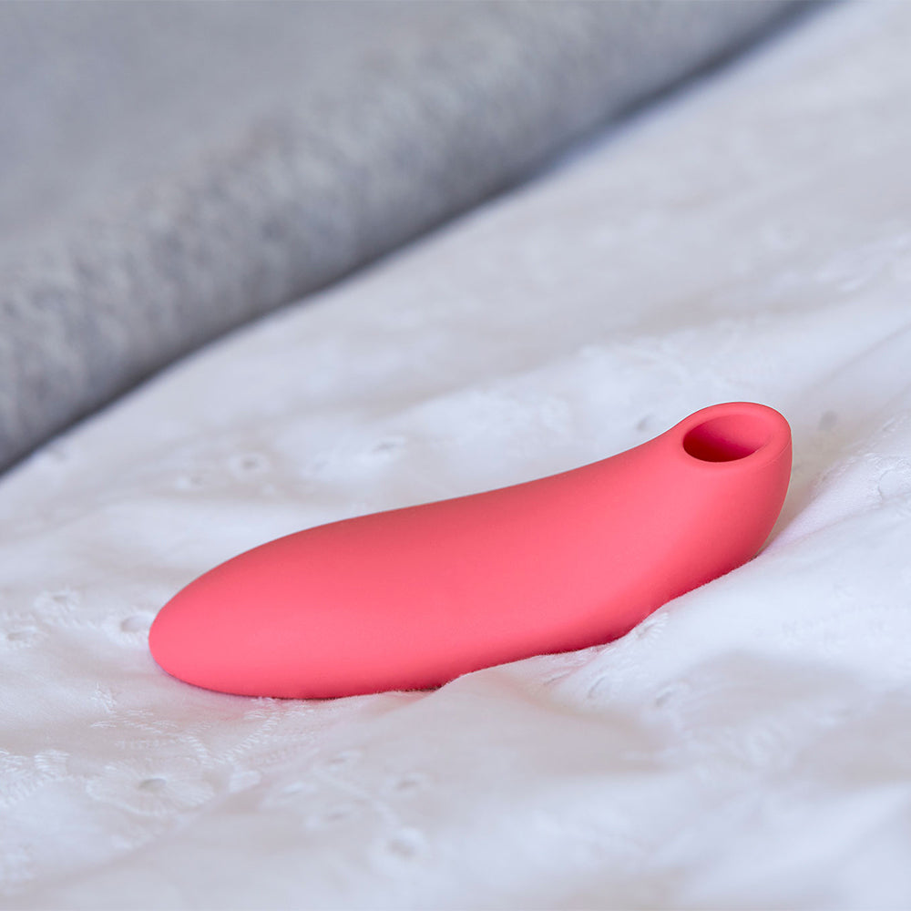 The Melt by We-Vibe pink in colour lying on bed sheets. There is a suction area up the top for clitoral stimulation. Sold at xesproducts.com.au xes products