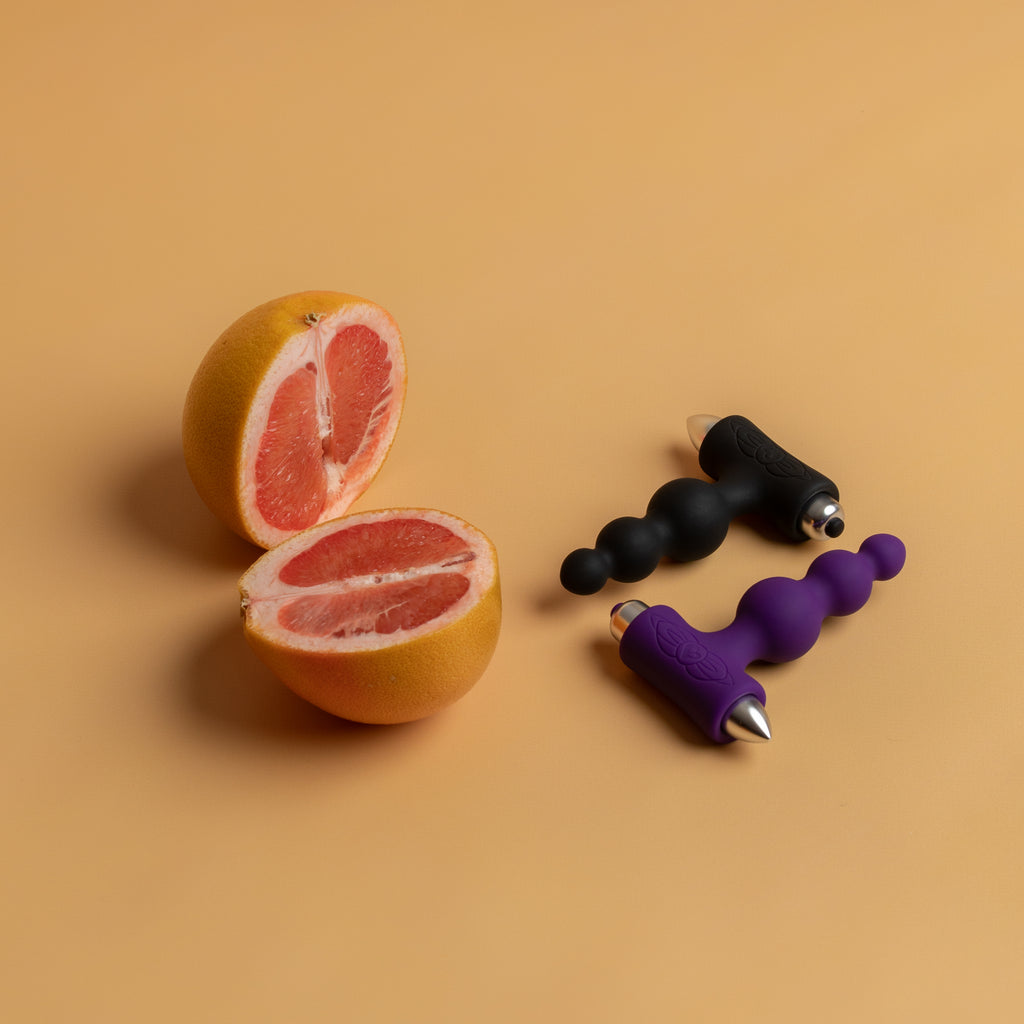 The black and purple petite sensations bubbles lying next to an open grapefruit.