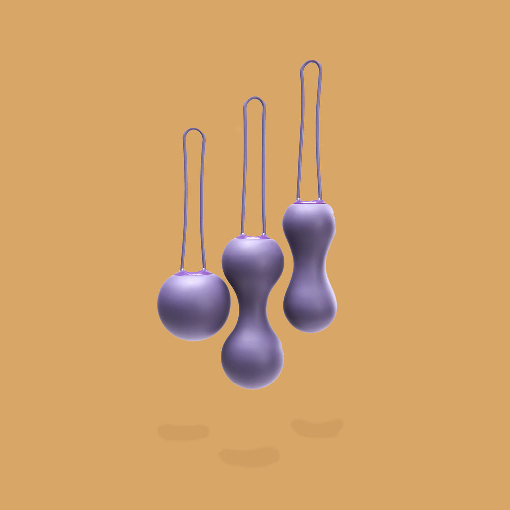 The 3 ami purple kegel balls lined up next to each other. The first is one round ball, the middle one is the biggest - it has two balls on each end connected by a narrower part, the last is more of an hourglass shape. Accessible sex toys by XES Products