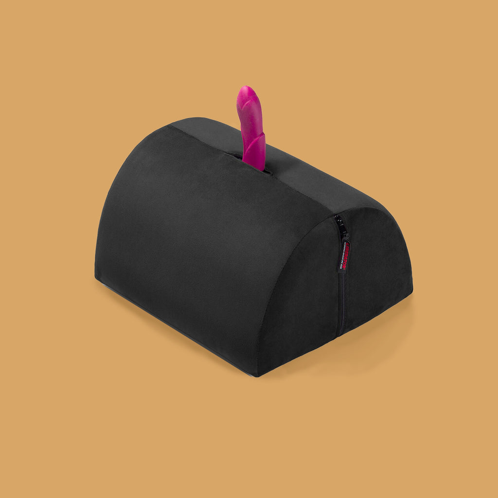 The Bon Bon positioning pillow by Liberator.  There is a pink dildo placed in the middle of the bon bon positioning pillow. The pillow is black and half of a cylinder. It is accessible and can be used for positioning, for accessibility and for relieving back pain.