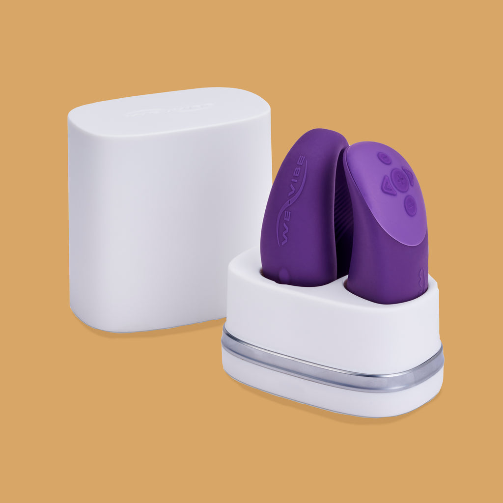 The Chorus by We-Vibe sitting in its charging socket. There is a cover for the charger placed at the back of the photo. The Chorus by We-Vibe is sold on XES Products as it promotes accessibility. 