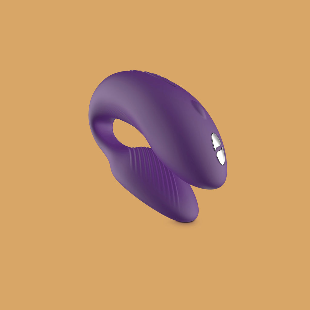The purple chorus by We-Vibe vibrator. The Chorus vibrator has a curved shape. One side of the vibrator has external ridges/ribbing for extra texture. The outer side of the vibrator shows two buttons that can be pressed to control the remote. 