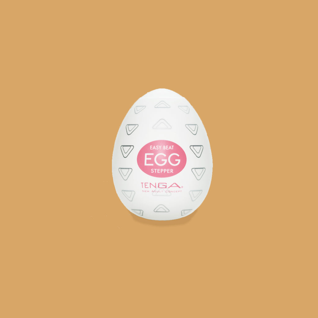 The Tenga Egg Stepper packaging. The outside shows the pattern that resembles the inside pattern. Looks like lots of triangles, described as "numerous rounded wedges." The writing colour on the stepper is pink. 